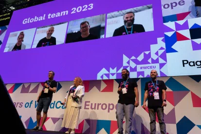 WCEU 2023 podium met op de achtergrond een enorm scherm en op de voorgrond, Sjoerd, Evangelia en José
