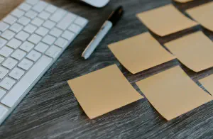A desk with keyboard, a pen and sticky notes stuck around